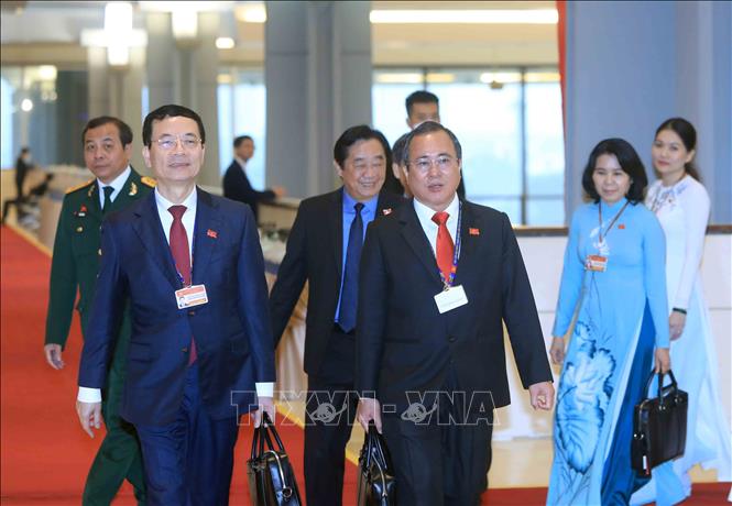 Trong ảnh: Ủy viên Trung ương Đảng, Bộ trưởng Bộ Thông tin và Truyền thông Nguyễn Mạnh Hùng (bên trái) và các đại biểu đến dự Đại hội, sáng 28/1. Ảnh: TTXVN