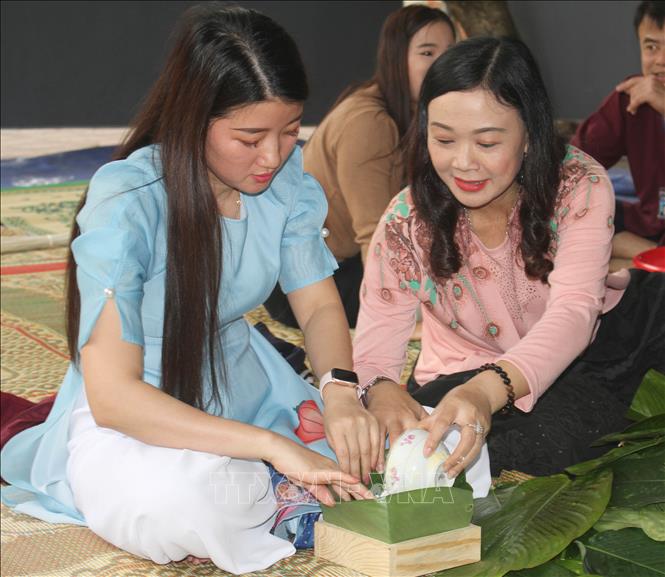 Trong ảnh: Khách tham quan trải nghiệm gói bánh chưng tại 
