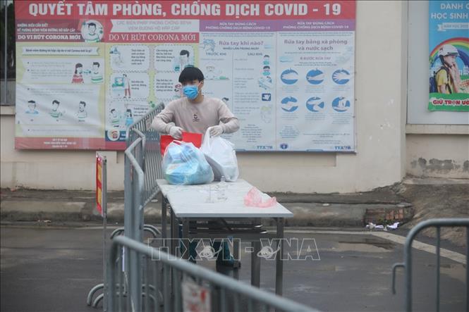 Trong ảnh: Người nhà gửi đồ tiếp tế cho người bên trong khu cách ly. Ảnh: Minh Quyết - TTXVN