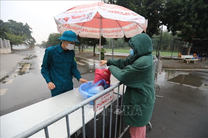 Trong ảnh: Người thân mang đồ vào cho học sinh trường Tiểu học Xuân Phương diện cách ly chiều 31/1. Ảnh: Thành Đạt - TTXVN