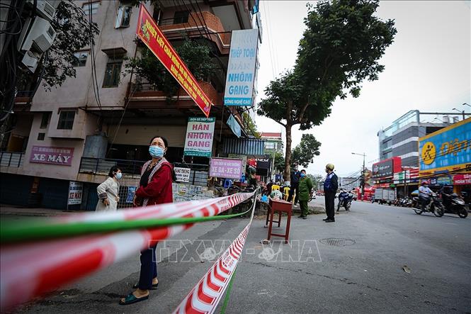Trong ảnh: Người dân chờ đợi lấy thực phẩm bên trong khu vực giới hạn cách ly theo dõi COVID-19. Ảnh: Trọng Đạt - TTXVN