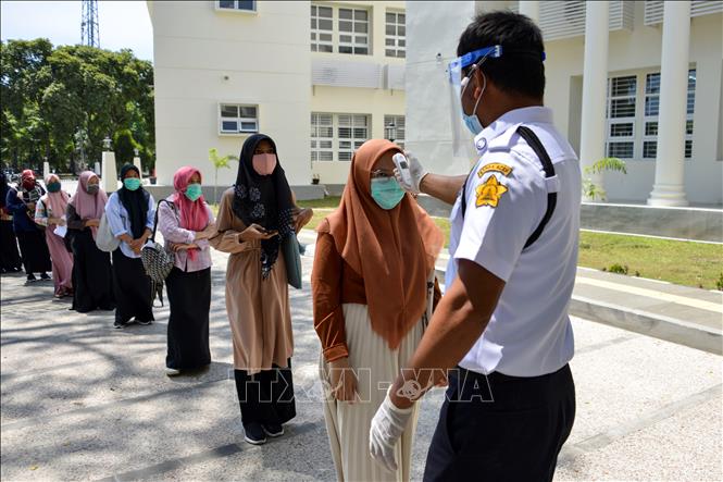 Trong ảnh: Kiểm tra thân nhiệt của học sinh tham dự kỳ thi đại học tại Banda Aceh, Indonesia nhằm ngăn dịch COVID-19 lây lan ngày 5/7/2020. Ảnh: AFP/TTXVN