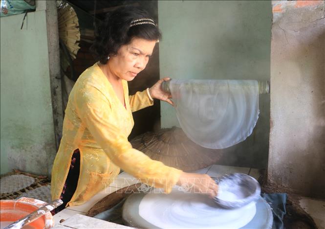 Trong ảnh: Bà Trần Thị Tuyết Mai, xã Lục Sĩ Thành, huyện Trà Ôn, tỉnh Vĩnh Long tỉ mỉ tráng từng chiếc bánh. Ảnh: Lê Thúy Hằng – TTXVN.