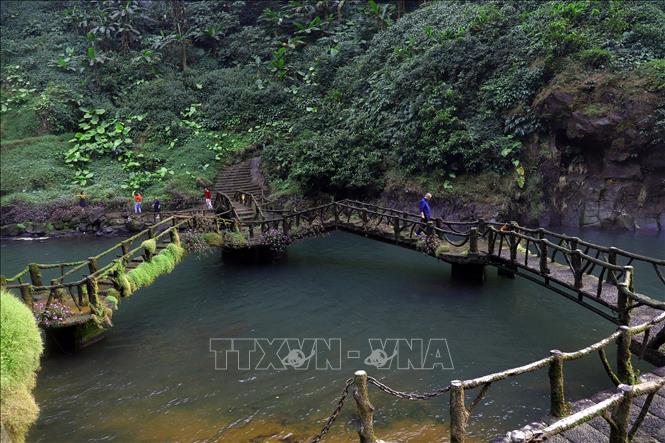 Trong ảnh: Cây cầu nhỏ nối liền hai bờ dưới chân thác quanh năm rêu phủ. Ảnh: Huy Hùng - TTXVN