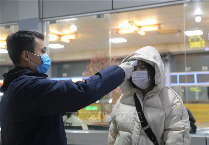 Trong ảnh: Hành khách ngoài bắt buộc đeo khẩu trang còn được kiểm tra thân nhiệt trước khi vào trong bến xe Nước Ngầm. Ảnh: Hoàng Hiếu - TTXVN