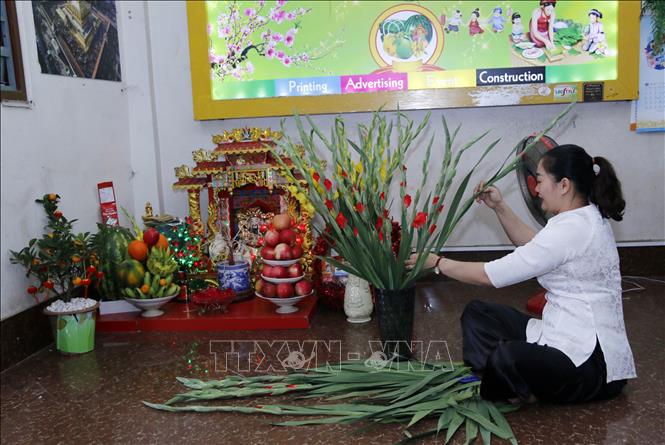 Trong ảnh: Chị Hương (vợ anh Nam) cắm một lọ hoa dơn - loại hoa người Việt hay dùng trang trí nhà cửa mỗi dịp đón Tết. Ảnh: Phạm Kiên - Phóng viên TTXVN tại Lào