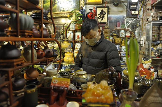 Trong ảnh: Một người tham quan tại gian hàng bán đồ gốm sứ tại chợ Bát Tràng. Ảnh Mạnh Khánh/TTXVN