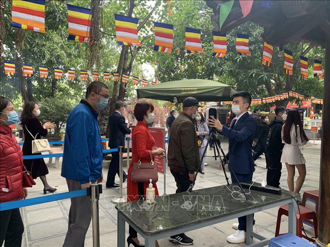 Trong ảnh: Người dân đi lễ tại Chùa Hà, quận Cầu Giấy, Hà Nội được đo kiểm tra thân nhiệt trước khi vào trong khuôn viên chùa. Ảnh: Nguyễn Cúc - TTXVN