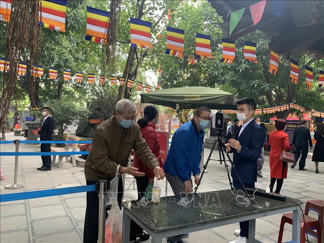 Trong ảnh: Người dân đi lễ tại Chùa Hà, quận Cầu Giấy, Hà Nội được đo kiểm tra thân nhiệt và rửa tay sát khuẩn trước khi vào trong khuôn viên chùa. Ảnh: Nguyễn Cúc - TTXVN
