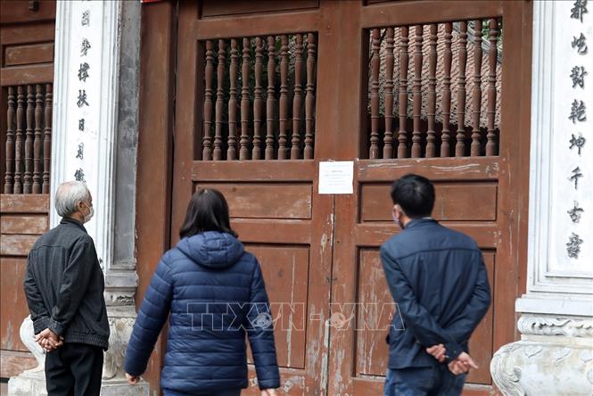 Trong ảnh: Người dân đọc thông báo đóng cửa tại Đền - Đình Kim Liên. Ảnh: Phan Tuấn Anh - TTXVN 