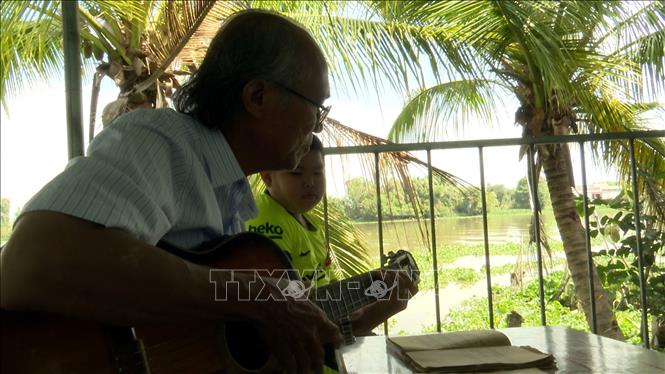 Trong ảnh: Soạn giả Diệp Vàm Cỏ đàn bài vọng cổ vừa sáng tác. Ảnh: Thanh Bình-TTXVN