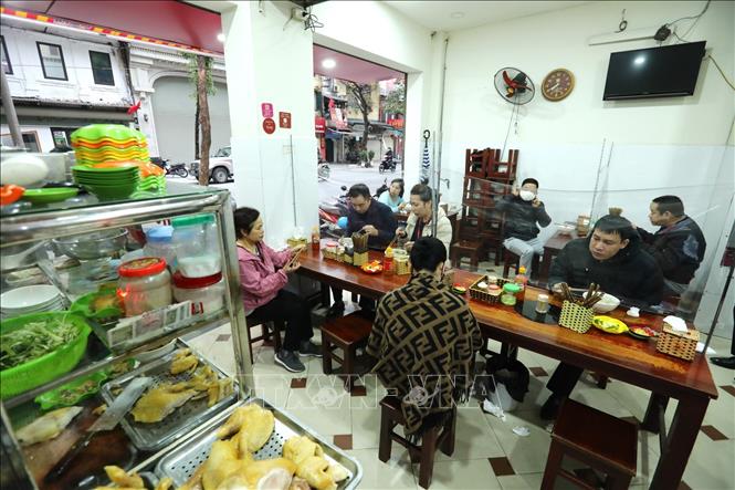 Trong ảnh: Hàng phở trên phố Nguyễn Hữu Huân phục vụ trong nhà, đảm bảo vệ sinh khử khuẩn, thực hiện giãn cách tối thiểu 2 mét và có vách ngăn. Ảnh: Thành Đạt - TTXVN