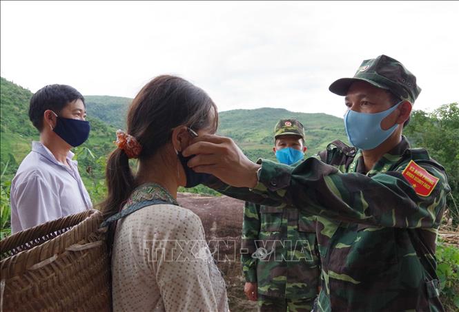 Trong ảnh: Bộ đội Biên phòng tỉnh Điện Biên  phát khẩu trang miễn phí và hướng dẫn cách thức sử dụng, đeo khẩu trang đúng cách cho đồng bào đi nương tại khu vực biên giới giáp Lào và Trung Quốc. Ảnh: Xuân Tiến-TTXVN