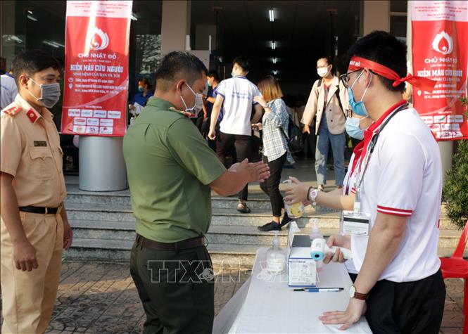 Trong ảnh: Các tình nguyện viên kiểm tra thân nhiệt và sát khuẩn trước khi đăng ký hiến máu. Ảnh: Trung Kiên - TTXVN