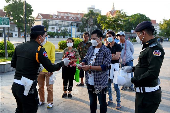 Trong ảnh: Cảnh sát phát khẩu trang cho người dân để phòng dịch COVID-19 tại Phnom Penh, Campuchia ngày 12/11/2020. Ảnh: AFP/TTXVN