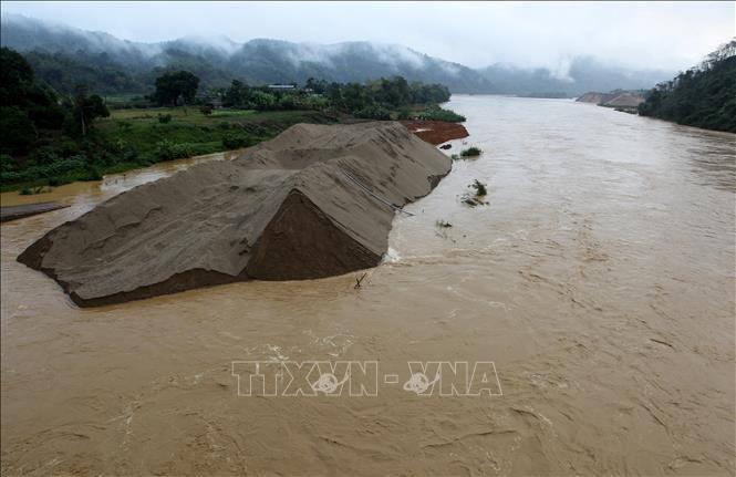 Cát sỏi của doanh nghiệp khai thác trên sông Hồng không kịp di chuyển khi lũ lớn tràn về, trôi xuống sông Hồng làm ảnh hưởng đến dòng chảy của sông, đoạn qua thành phố Lào Cai. Ảnh: Quốc Khánh - TTXVN