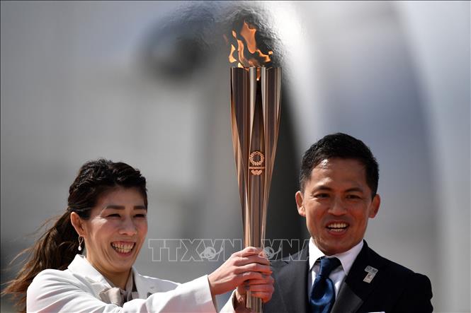 Trong ảnh (tư liệu): Vận động viên Nhật Bản ba lần giành Huy chương Vàng Olympic Saori Yoshida (trái) và Tadahiro Nomura (phải) giơ cao ngọn đuốc Olympic Tokyo 2020 sau khi đuốc được chuyển về từ Hy Lạp, tại căn cứ không quân Matsushima ở Higashimatsushima, tỉnh Miyagi ngày 20/3/2020. Ảnh: AFP/TTXVN