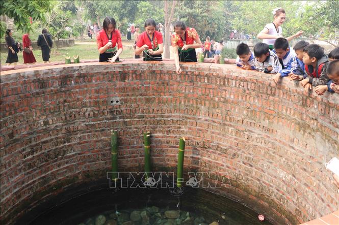 Các thiếu nữ Thái múc nước trong mó nước để rửa tay, rửa mặt cho người dân, du khách. Theo tục lệ, sau khi chiến thắng giặc trở về, Nàng Han cởi xiêm y, tắm gội ở mó nước rồi bay lên trời. Ảnh: Nguyễn Oanh-TTXVN