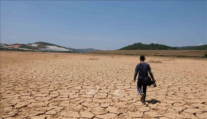 Trong ảnh: Người dân có thể đi bộ hoặc chạy xe thoải mái trên lòng hồ Đankia cạn trơ đáy. Ảnh: Nguyễn Dũng – TTXVN 
