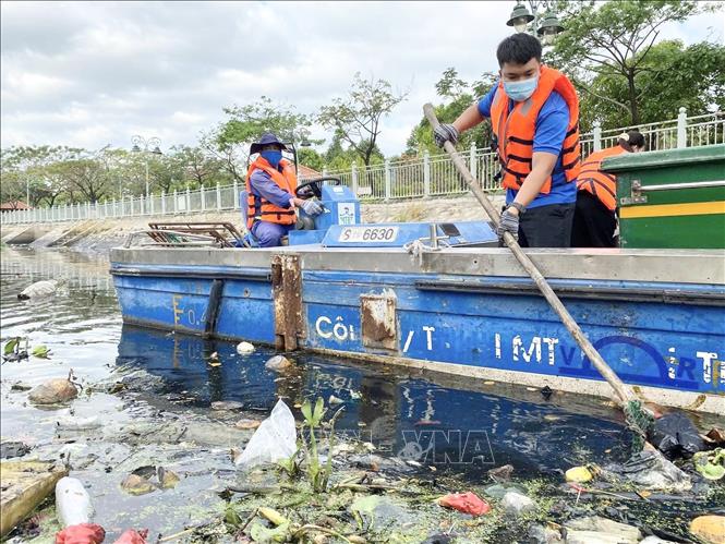 Trong ảnh: Lực lượng công nhân vệ sinh vớt rác làm sạch kênh. Ảnh: TTXVN phát.
