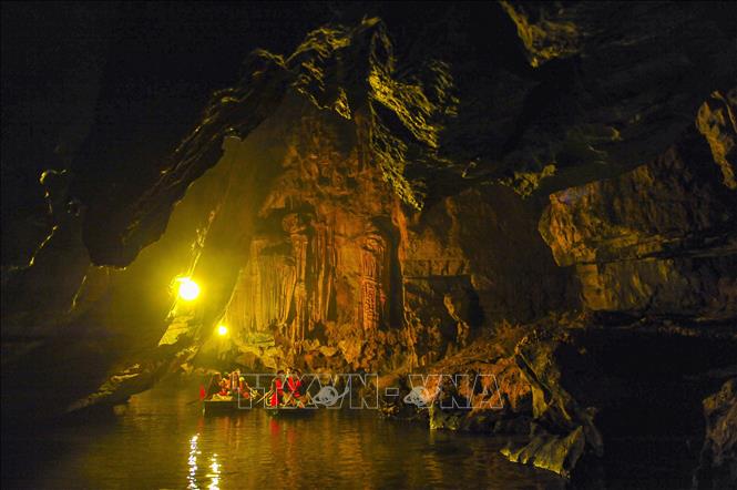 Trong ảnh: Du khách khám phá hang động trong lòng di sản bằng thuyền. Quần thể danh thắng Tràng An là một vùng du lịch tổng hợp gồm các di sản văn hóa và thiên nhiên thế giới do UNESCO công nhận ở Ninh Bình. Quần thể danh thắng Tràng An trải rộng hơn 2.000 ha, bao gồm khu du lịch sinh thái Tràng An, khu du lịch Tam Cốc – Bích Động, cố đô Hoa Lư... Với vẻ đẹp thiên nhiên hùng vĩ, Tràng An được ví như một vịnh Hạ Long trên cạn thu hút du khách đến chiêm ngưỡng. Ảnh: Minh Đức - TTXVN