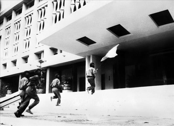 11 giờ 30 phút, ngày 30/4/1975, ta kéo cờ chiến thắng trên nóc dinh Độc Lập. Trong ảnh: Trung úy Bùi Quang Thận, Đại đội trưởng xe tăng 4 (cầm cờ, phía trước) cùng 3 chiến sĩ của Lữ đoàn Tăng – Thiết giáp 203, Sư đoàn 304, Quân đoàn 2 tiến vào cắm cờ trên nóc Phủ Tổng thống Ngụy quyền Sài Gòn. Ảnh: Vũ Tạo – TTXVN