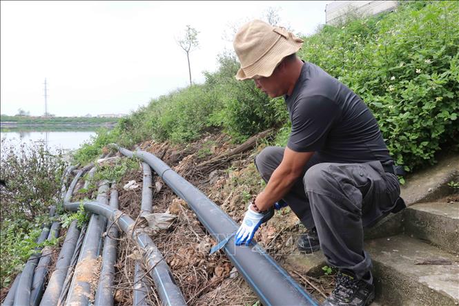 Trong ảnh: Dỡ bỏ ống nước dẫn nước mặt vào các doanh nghiệp sản xuất giấy tại Phong Khê, thành phố Bắc Ninh. Ảnh: Đinh Văn Nhiều- TTXVN