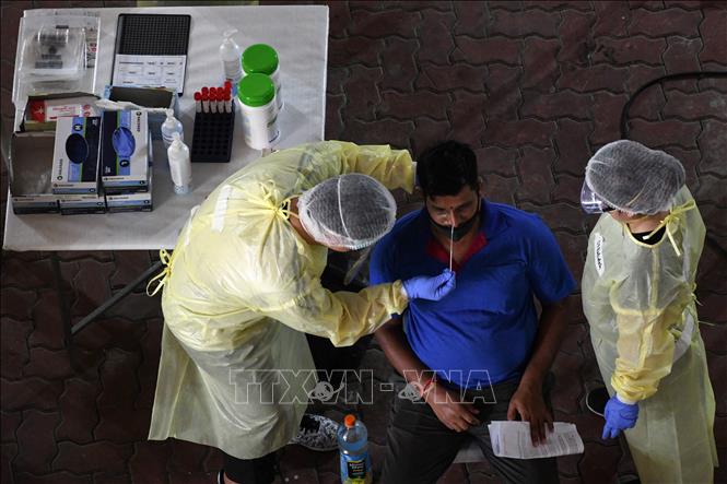 Trong ảnh: Nhân viên y tế lấy mẫu xét nghiệm COVID-19 cho công nhân tại Singapore ngày 10/6/2021. Ảnh: AFP/TTXVN