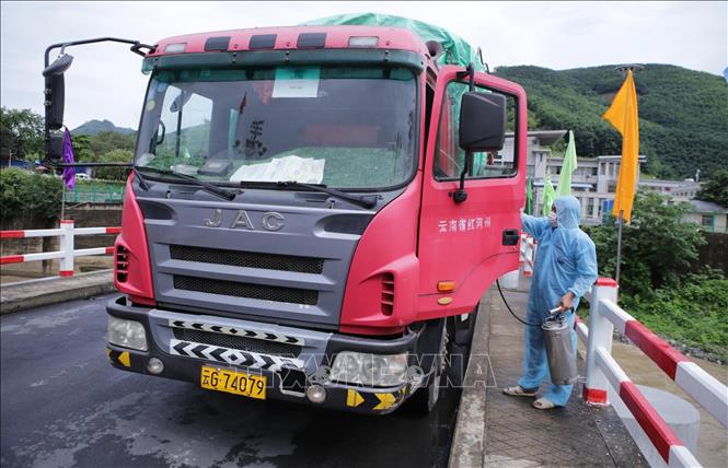 Trong ảnh: Các phương tiện vận chuyển hàng hóa xuất, nhập khẩu của mỗi nước đều dừng giữa cầu hữu nghị, nhân viên lái xe nhận xe và phun trùng khử khuẩn khoang buồng lái và tay cầm phòng chống dịch COVID-19. Ảnh: Quý Trung – TTXVN