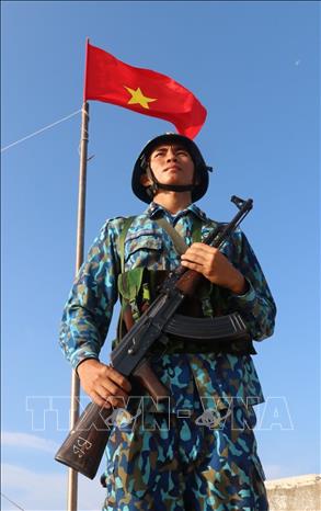 Trong ảnh: Chiến sỹ Nguyễn Xuân Quý – đảo Đá Tây A (quần đảo Trường Sa) nghiêm trang đứng gác dưới cờ Tổ quốc. Ảnh: Sỹ Tuyên – TTXVN