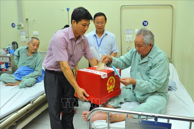 Trong ảnh: Nhân viên khu vực bỏ phiếu số 3, phường Bạch Đằng, quận Hai Bà Trưng (Hà Nội) mang hòm phiếu đến Bệnh viện Hữu Nghị để các bệnh nhân không tự vận động được bỏ phiếu bầu cử đại biểu Quốc hội khóa XIV. Ảnh: Minh Đức – TTXVN

