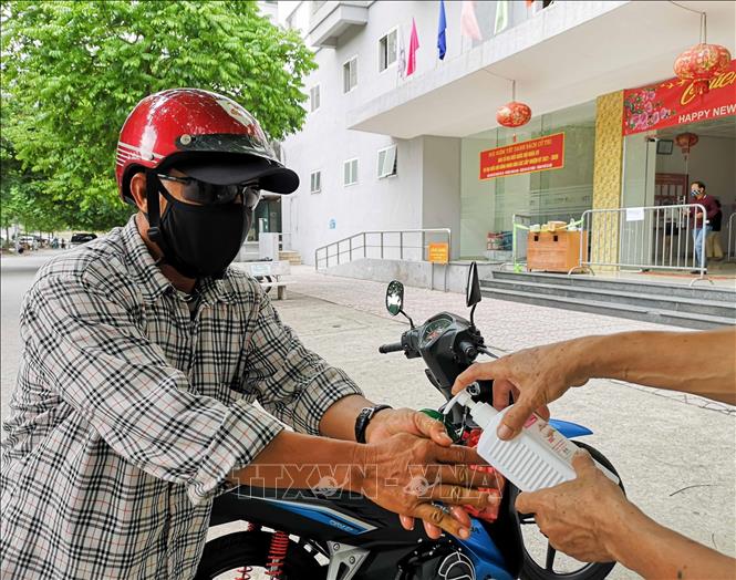 Trong ảnh: Người tới gửi đồ cho cư dân đều sát khuẩn tay, để đồ ở bàn và không tiếp xúc. Ảnh: Thanh Tùng - TTXVN 