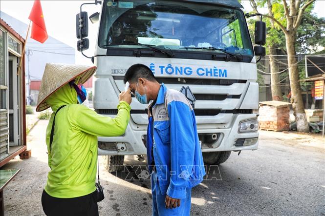 Trong ảnh: Các chủ phương tiện ra vào thôn đều phải xuống khai báo y tế, kiểm tra thân nhiệt cẩn thận. Ảnh: Tuấn Anh - TTXVN
