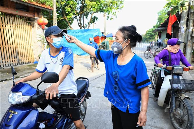 Trong ảnh: Các bà, các cô thuộc hội Phụ nữ thôn Thù Lỗ, xã Liên Hà, huyện Đông Anh kiểm tra nhiệt độ của người dân mỗi khi ra vào. Ảnh: Thành Đạt - TTXVN