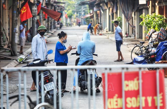 Trong ảnh: Tại thôn Thù Lỗ, xã Liên Hà, huyện Đông Anh, các bà, các mẹ thuộc hội Phụ nữ túc trực chốt phòng dịch ghi lại lịch trình đi lại của những người lạ đi vào thôn. Ảnh: Tuấn Anh - TTXVN
