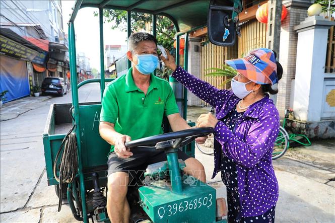 Trong ảnh: Các bà, các mẹ trong hội Phụ nữ kiểm tra thân nhiệt rất cẩn thận không bỏ xót một ai dù là người thân quen trong thôn. Ảnh: Thành Đạt - TTXVN