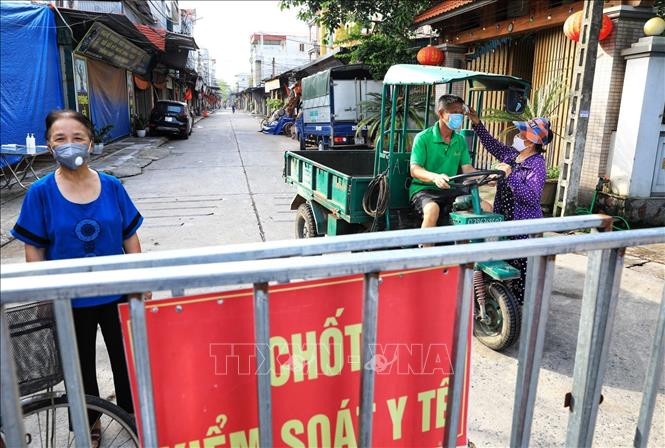Trong ảnh: Các bà, các mẹ trong hội Phụ nữ kiểm tra thân nhiệt rất cẩn thận không bỏ xót một ai dù là người thân quen trong thôn. Ảnh: Thành Đạt - TTXVN