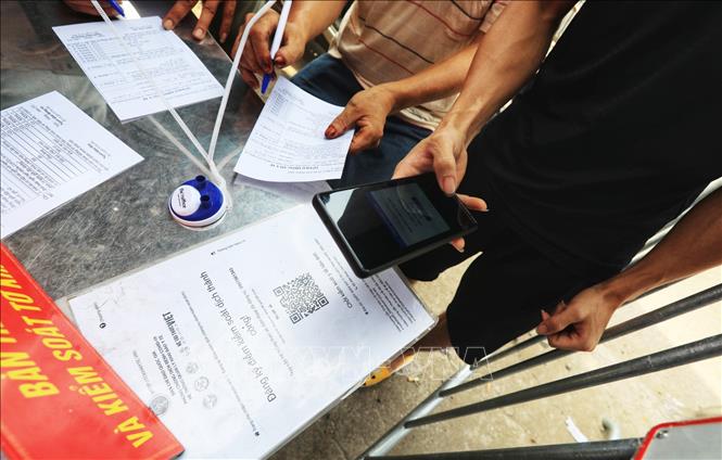 Trong ảnh: Người dân đi qua chốt kiểm dịch giáp ranh giữa xã Vân Hà, Đông Anh với huyện Từ Sơn, Bắc Ninh phải khai báo y tế bằng cách quét mã QR-code. Ảnh: Tuấn Anh - TTXVN