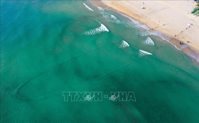 Trong ảnh: Lưới được thả thành hình vòng cung và dùng sức người kéo từ từ khép hai đầu lưới lại để gom thủy sản. Ảnh: Trần Lê Lâm – TTXVN