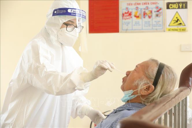 Nhân viên y tế lấy mẫu xét nghiệm COVID-19 cho bệnh nhân, người nhà tại các khoa, phòng. Ảnh: Minh Quyết - TTXVN