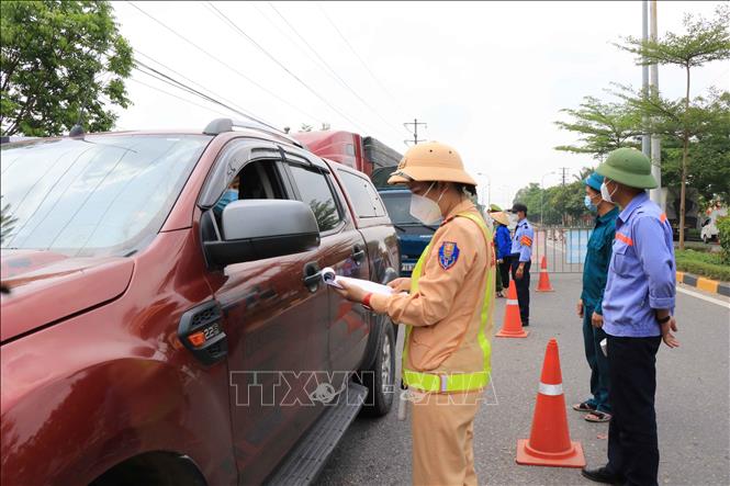 Trong ảnh: Đại úy Nguyễn Thị Thu Hường, Đội Cảnh sát giao thông, Công an huyện Tiên Du, kiểm tra giấy tờ lưu thông của các lái xe ra vào chốt kiểm soát dịch tại khu công nghiệp Tiên Sơn. Ảnh: Thanh Thương- TTXVN