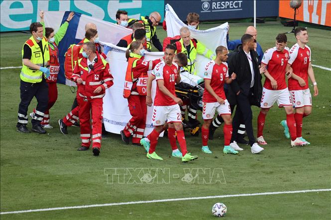 Trong ảnh: Các tuyển thủ Đan Mạch hỗ trợ nhân viên y tế chuyển tiền vệ Christian Erikssen rời sân khi anh bất ngờ ngã gục trong trận gặp đội Phần Lan ở bảng B, EURO 2020 tại Copenhagen ngày 12/6/2021. Ảnh: AFP/TTXVN