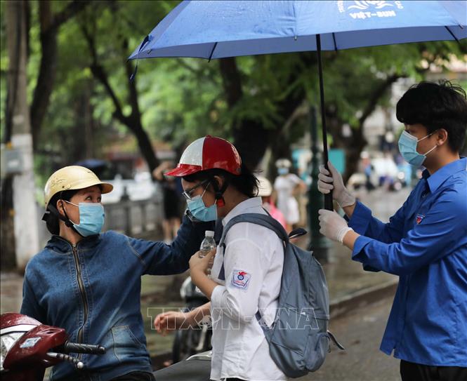 Trong ảnh: Phụ huynh đưa thí sinh tới điểm thi trường THPT Trần Nhân Tông trong những cơn mưa lớn. Ảnh: Thanh Tùng - TTXVN