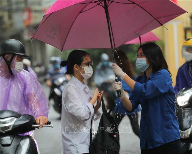Trong ảnh: Phụ huynh đưa thí sinh tới điểm thi trường THPT Trần Nhân Tông trong những cơn mưa lớn. Ảnh: Thanh Tùng - TTXVN
