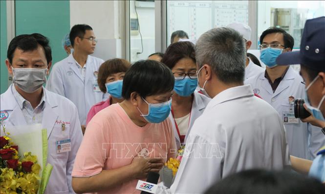 Hình ảnh bệnh nhân Li Ding (áo hồng) - một trong hai người đầu tiên nhiễm SARS-CoV-2 tại Việt Nam cúi đầu cảm ơn các bác sỹ Việt Nam trong ngày xuất viện (12/2/2020) được phóng viên TTXVN ghi lại. Ảnh: Đinh Hằng – TTXVN