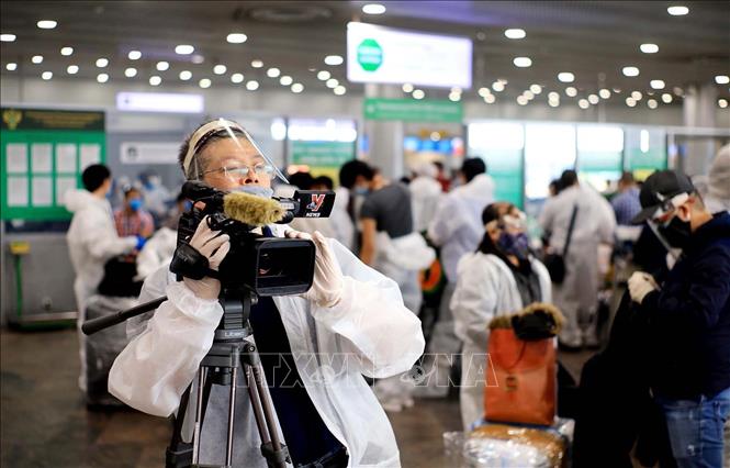 Trưởng Cơ quan thường trú TTXVN tại Moskva Bùi Duy Trinh đưa tin về chuyến bay đầu tiên đưa hơn 300 công dân Việt Nam từ Liên bang Nga về nước trong bối cảnh đại dịch COVID-19, tại sân bay Sheremetyevo, tháng 5/2020. Ảnh: TTXVN