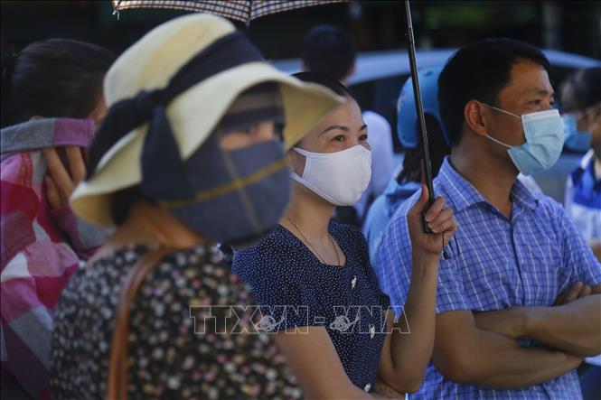 Ánh mắt đợi chờ và lo lắng của một phụ huynh có con tham gia kiểm tra đợt này. Ảnh: Nam Sương - TTXVN