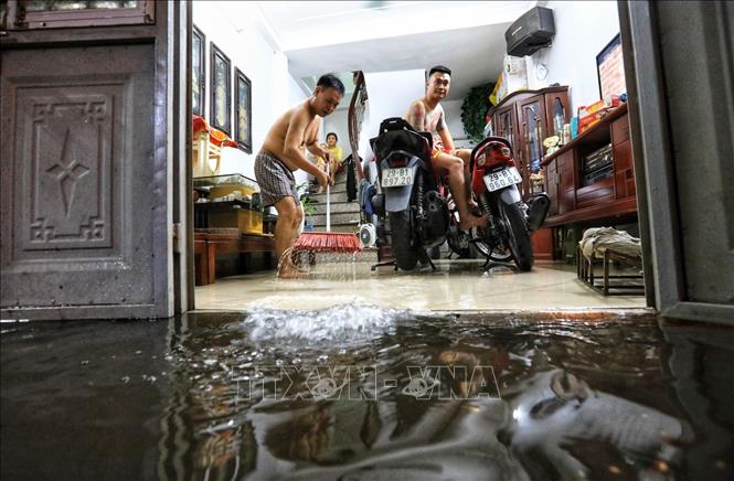Trong ảnh: 1 hộ gia đình ngõ 90, phố Đội Cấn (Hà Nội) tát nước từ trong nhà ra sau cơn mưa lớn tối 22/6. Ảnh: Thành Đạt - TTXVN 