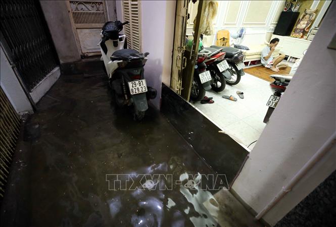 Trong ảnh: Người dân Hà Nội đã phải dùng nhiều biện pháp để ngăn nước tràn vào nhà sau cơn mưa to tối 22/6. Ảnh: Phạm Kiên - TTXVN