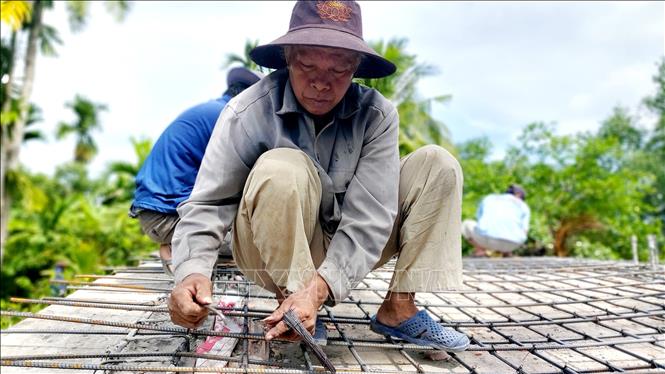Ông Võ Văn Hộ tích cực góp công sức tham gia xây cầu từ thiện. Ảnh: Thu Hiền - TTXVN
